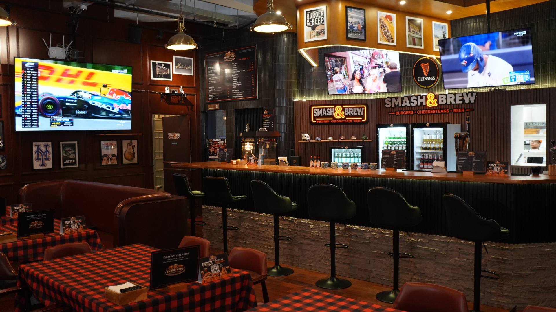 The bar at Smash & Brew — neon sign, brass lamps, the game on